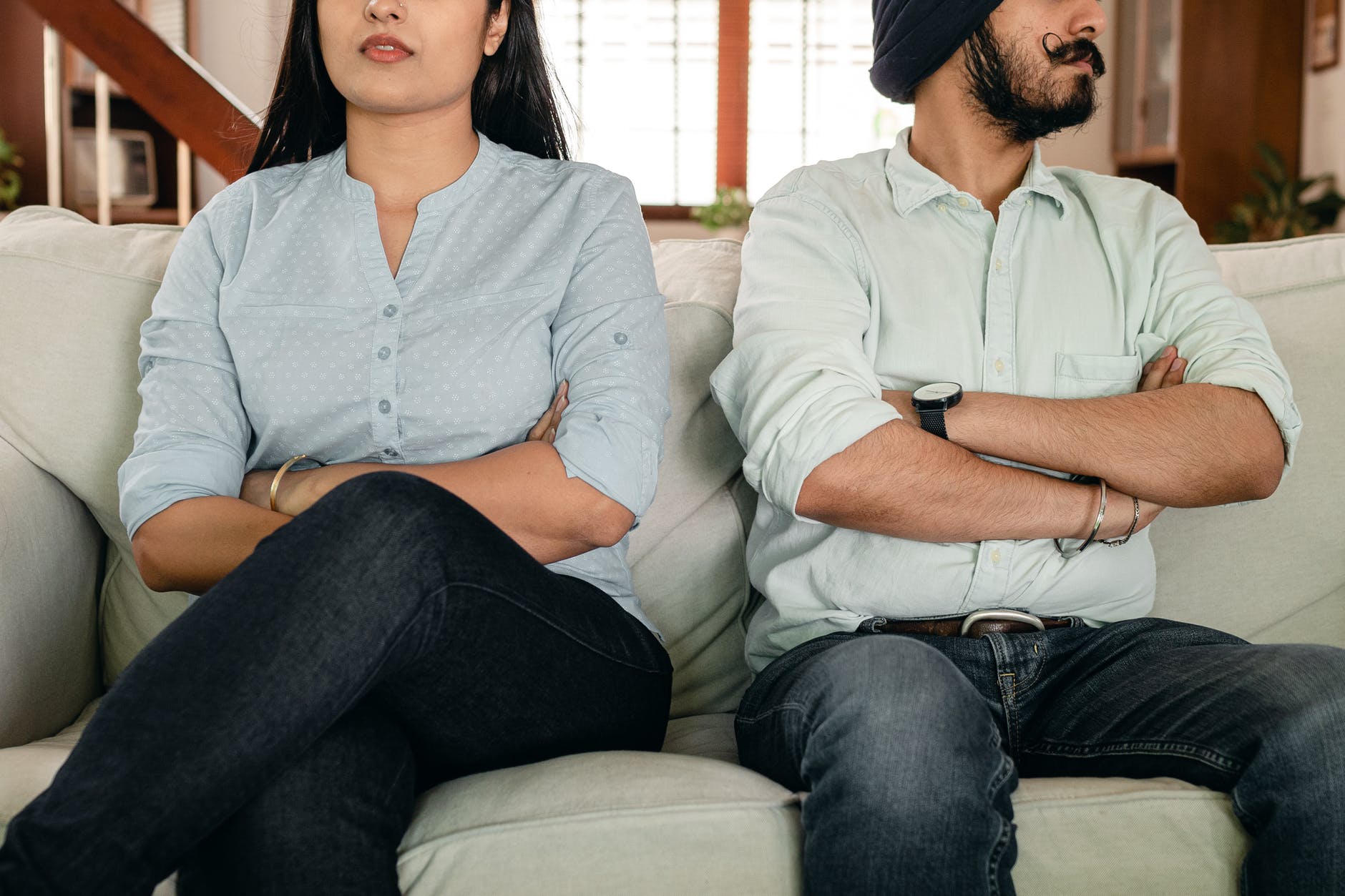 anonymous ethnic couple sitting on sofa having marriage issues