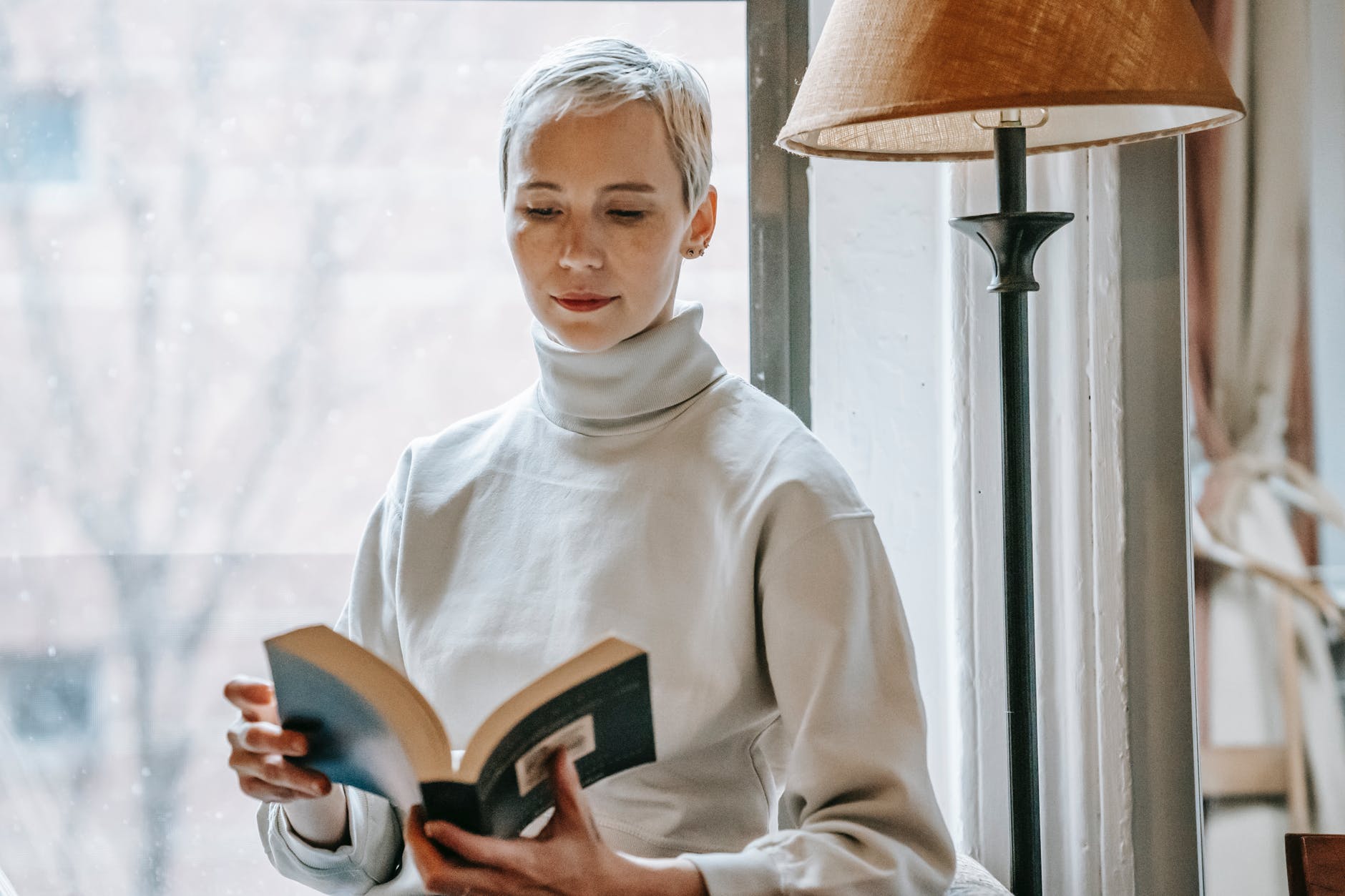 woman with opened interesting book near lamp