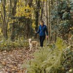 woman and dog walking at woods