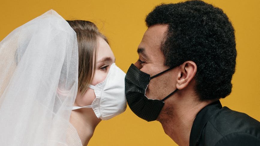 man in black suit jacket holding woman in white wedding dress
