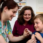 Nurse administering an intramuscular vaccination in the left shoulder