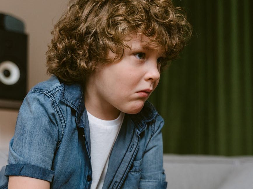 close up shot of a boy holding a video game controller while sitting on the sofa