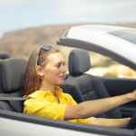 woman in yellow shirt driving a silver car