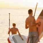 photo of man and woman holding a paddleboard