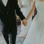 woman wearing white wedding gown holding hands with man while walking