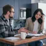 a man talking to a woman with documents on a desk