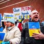 people holding anti war signs and protesting in the street