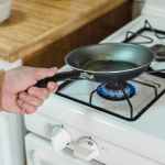 a person heating oil in a frying pan