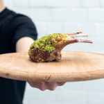 man holding meat on cutting board