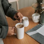 a person mixing a drink in a tall cup