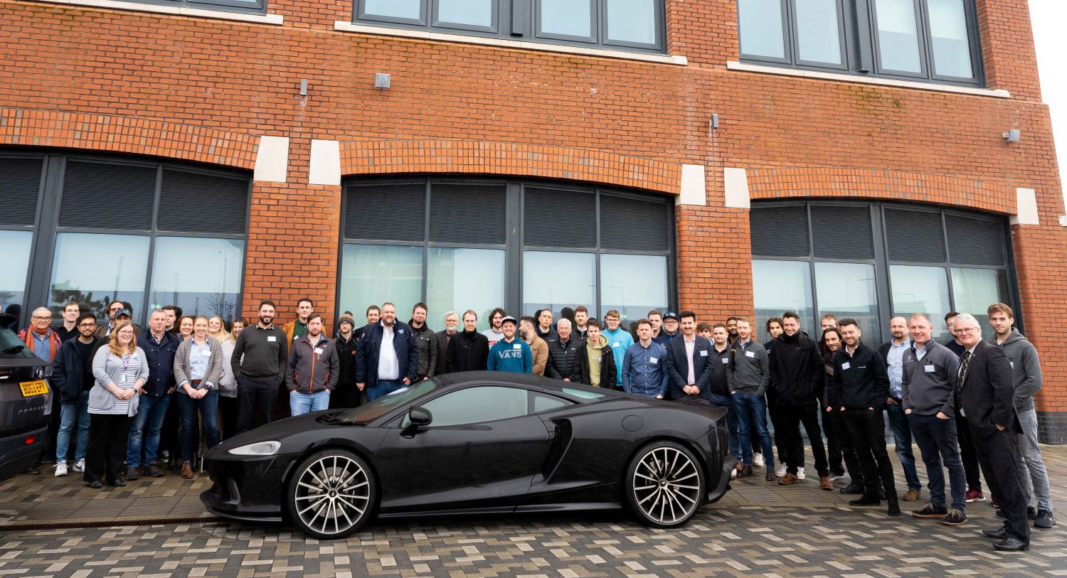 Students, staff and alumni with a McLaren