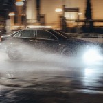 a black car driving through puddle of water