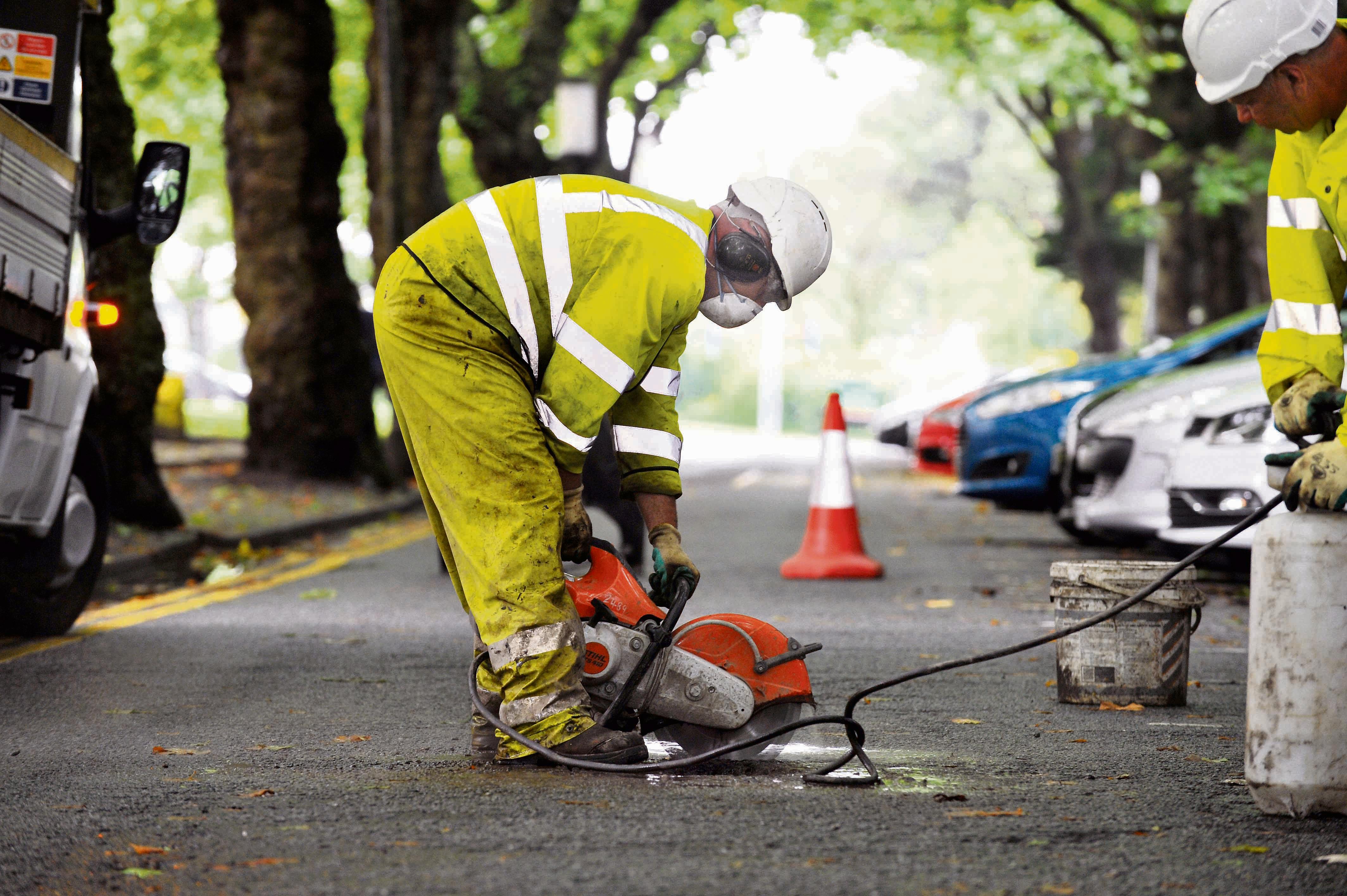 Road worker repairing a pothole on a Swansea road