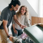 cheerful couple packing suitcase in sunny bedroom