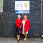 a dog sitting on the green grass near the lake