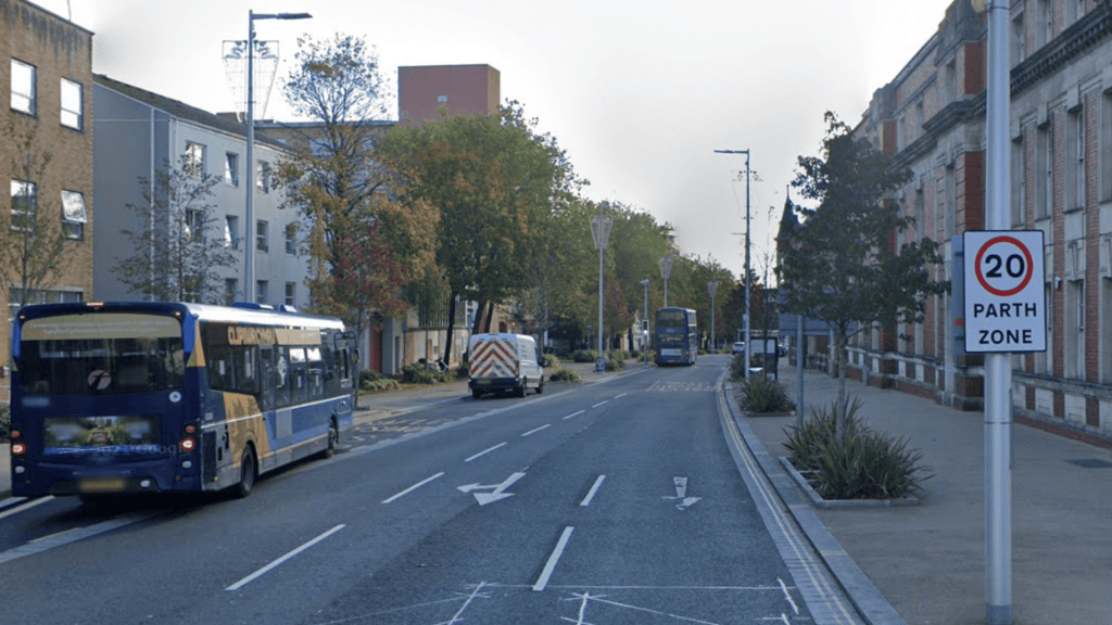 A 20mph zone sign on a Swansea street with a First Cymru bus heading away