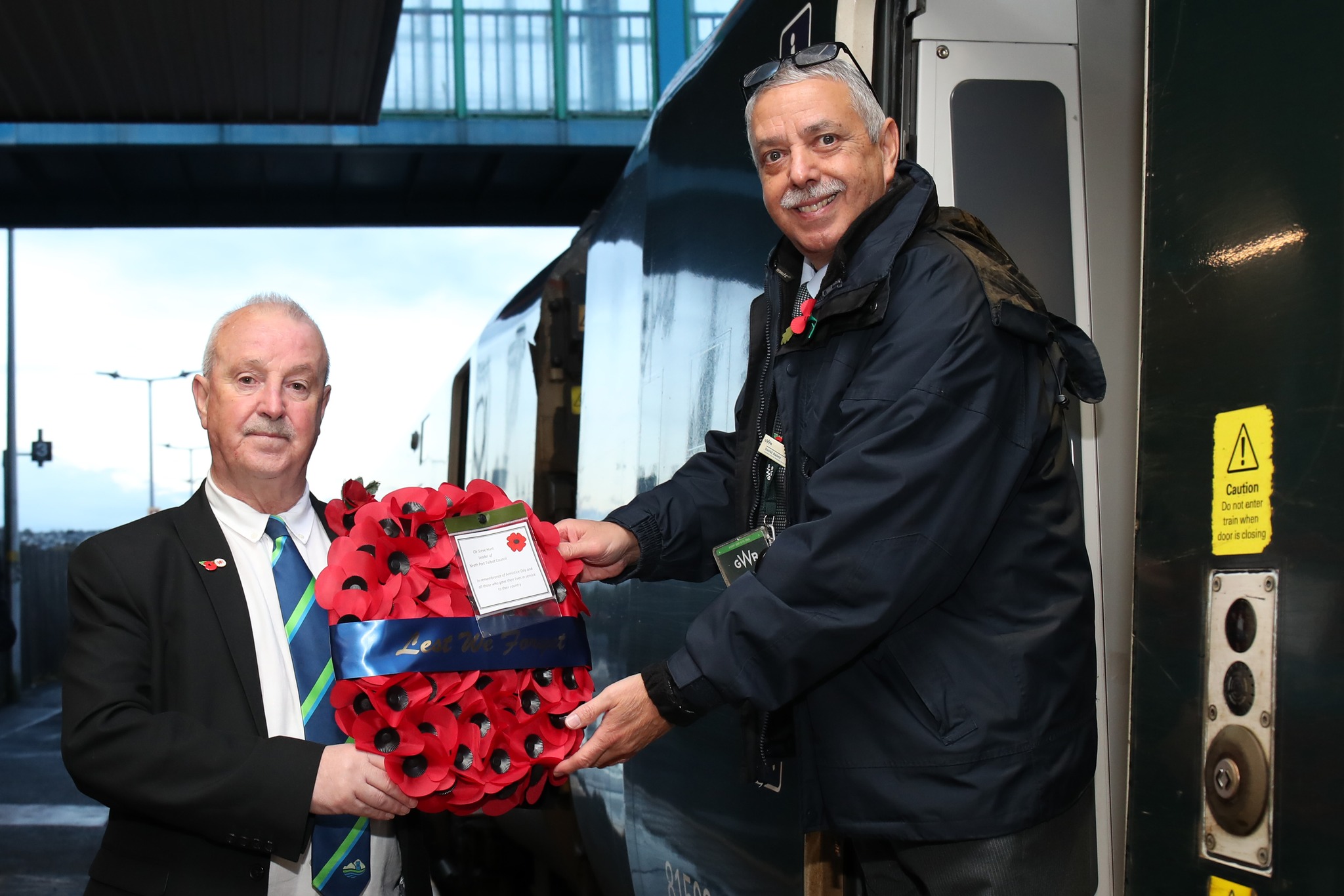 Leader of Neath & Port Talbot Council Steve Hunt hands over a wreath at Neath train station