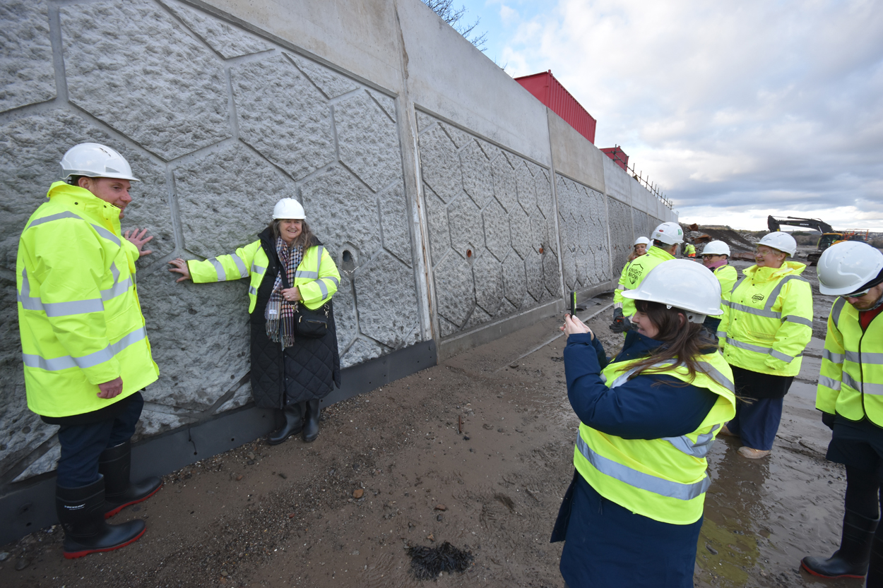 Tour guests inspect newly installed sea wall panels in Mumbles.