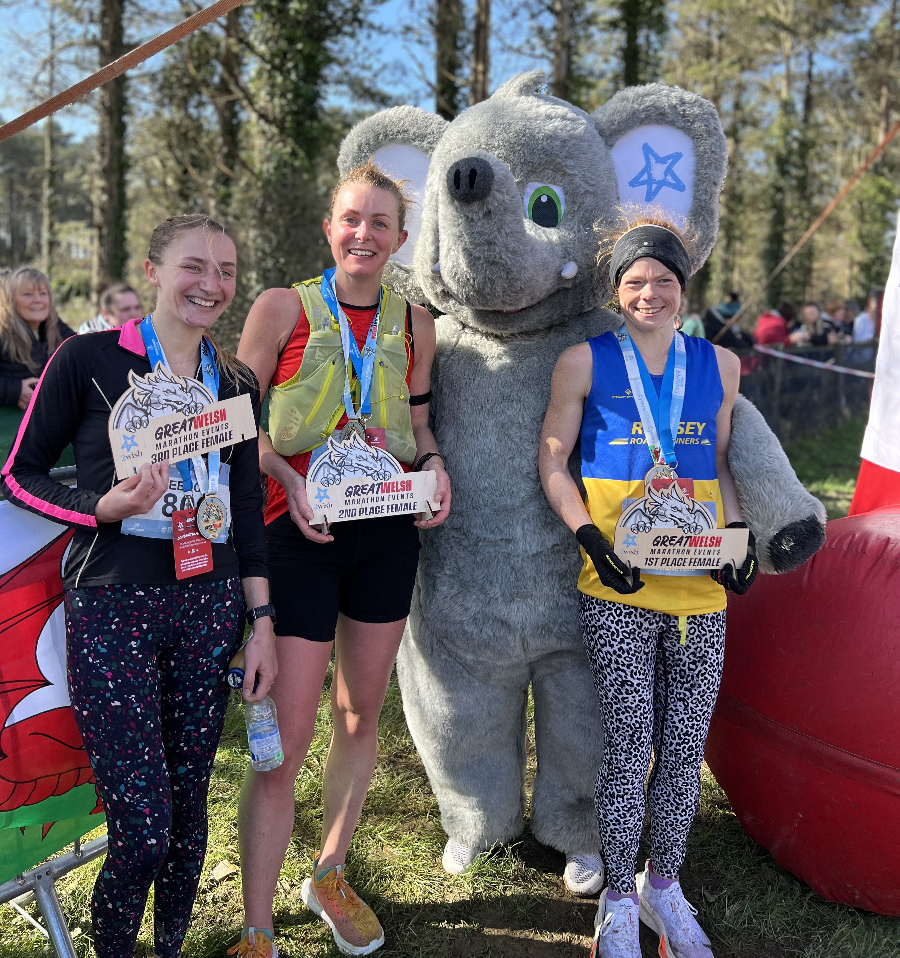 First place female winner, Hayley Weston of Romsey Road Runners, second placed Emma Wyatt Haines and third placed, Rebecca Stone standing with event sponsor 2Wish's mascot.