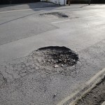 Close‑up of a pothole in an asphalt road surface, illustrating the type of damage drivers frequently encounter.
