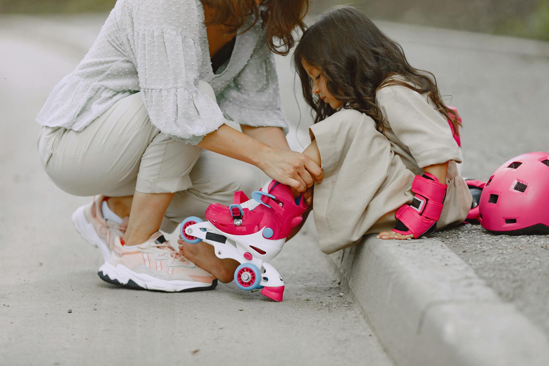 a parent helping her daughter wear rollerblades