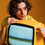 handsome guy holding a yellow tv