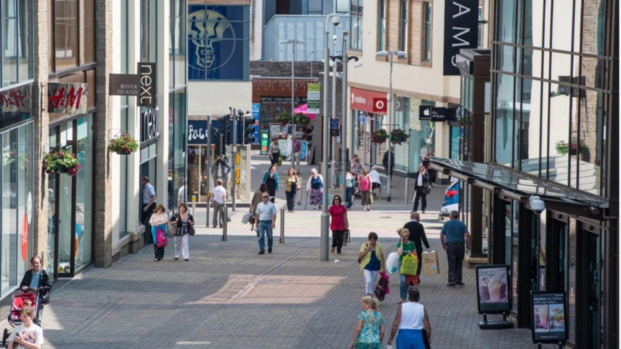 Shoppers walking through St Catherine's Walk shopping centre in Carmarthen High Street with River Island and Next stores visible