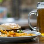 hamburger and fries beside mug with beer