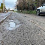 Large pothole on a country lane in South West Wales, highlighting the challenges of maintaining rural roads.