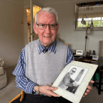David at home holding a photograph of his younger self in front of the Guildhall - one of Swansea's iconic clocks he once maintained