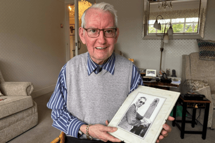 David at home holding a photograph of his younger self in front of the Guildhall - one of Swansea's iconic clocks he once maintained