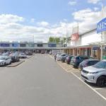 Street‑level image of Parc Trostre Retail Park with shopfronts, signage and pedestrian walkways visible.