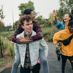 Two young men are racing through the park with their girlfriends on their backs.