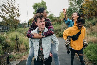 Two young men are racing through the park with their girlfriends on their backs.