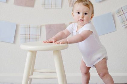 baby holding white wooden stool