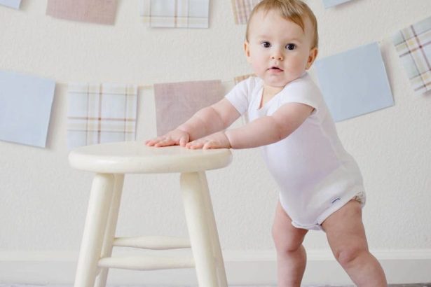 baby holding white wooden stool