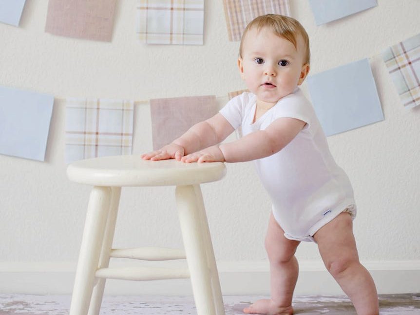 baby holding white wooden stool
