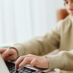 selective focus photo of a boy typing on his laptop
