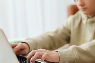 selective focus photo of a boy typing on his laptop