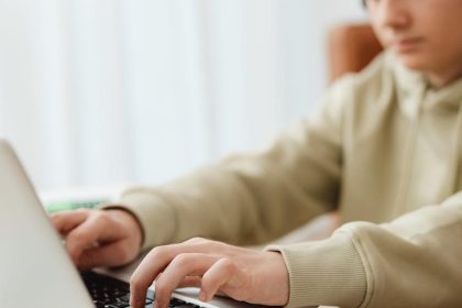 selective focus photo of a boy typing on his laptop