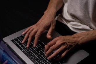 person in white long sleeve shirt using macbook pro