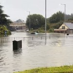File photo shows vehicles submerged at Cwmbwrla roundabout in Swansea during September 2025 flooding, later linked to the collapsed culvert beneath Cwmfelin Social Club.