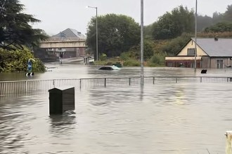 File photo shows vehicles submerged at Cwmbwrla roundabout in Swansea during September 2025 flooding, later linked to the collapsed culvert beneath Cwmfelin Social Club.