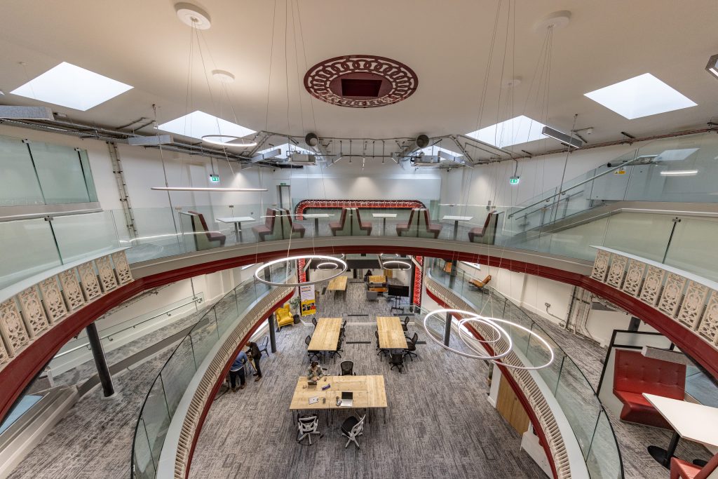Interior view through the open circular atrium of the renovated Palace Theatre in Swansea, showing three floors of modern workspace.