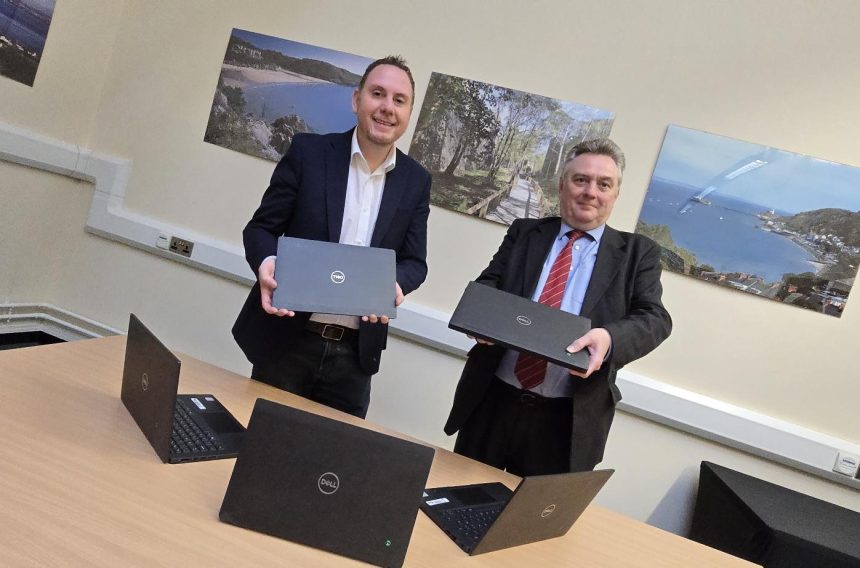 Rob Stewart and Robert Smith pictured with a stack of recycled laptops being distributed to young people in Swansea through a DVLA partnership.