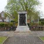 War memorials in the north‑east corner of People’s Park, Llanelli, featuring a statue of a coal miner and soldier with commemorative plaques.
