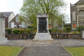 War memorials in the north‑east corner of People’s Park, Llanelli, featuring a statue of a coal miner and soldier with commemorative plaques.