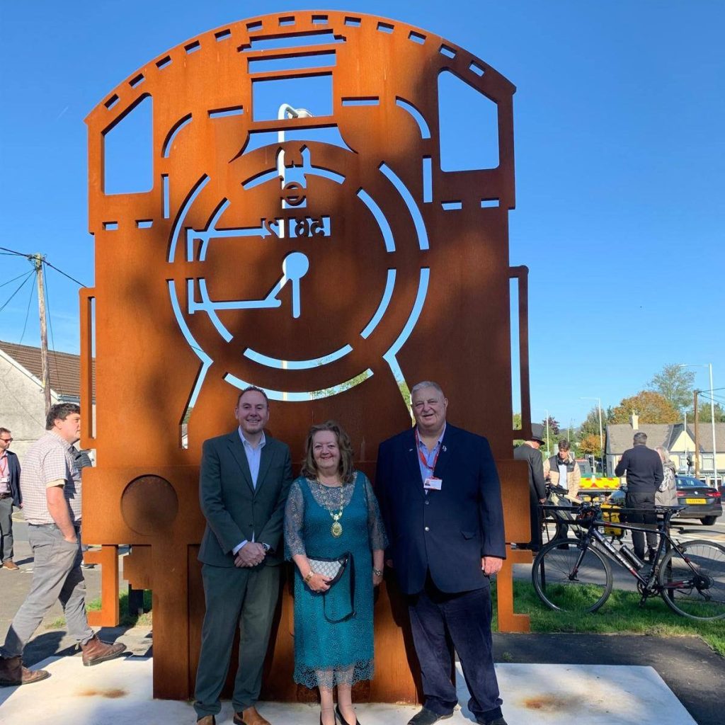 Cllr Rob Stewart, Cllr Patricia Evans and Cllr Dai Jenkins standing in front of the new steam locomotive sculpture in Gowerton.