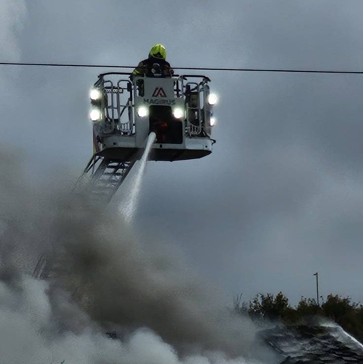 Mid and West Wales Fire and Rescue Service use a turntable ladder to fight the Neath house fire from above, as thick smoke fills the street.