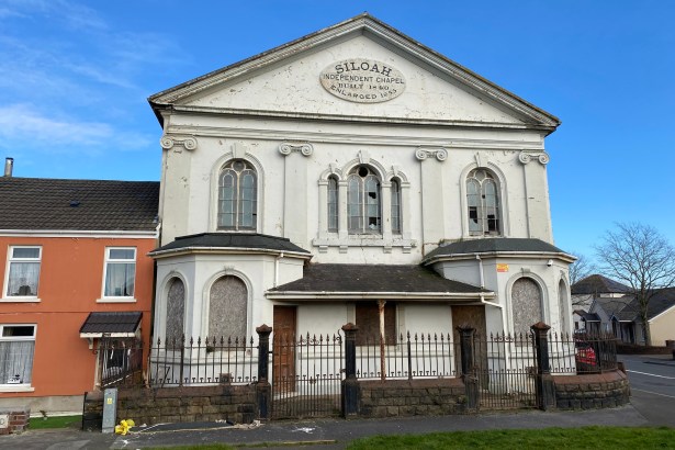 Exterior of Siloah Chapel in Llanelli showing boarded lower windows and broken upper panes, reflecting the building’s dilapidated condition before restoration.